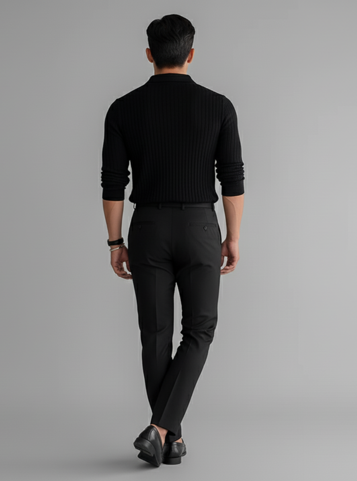 Man wearing a black sweater and pants on a gray background