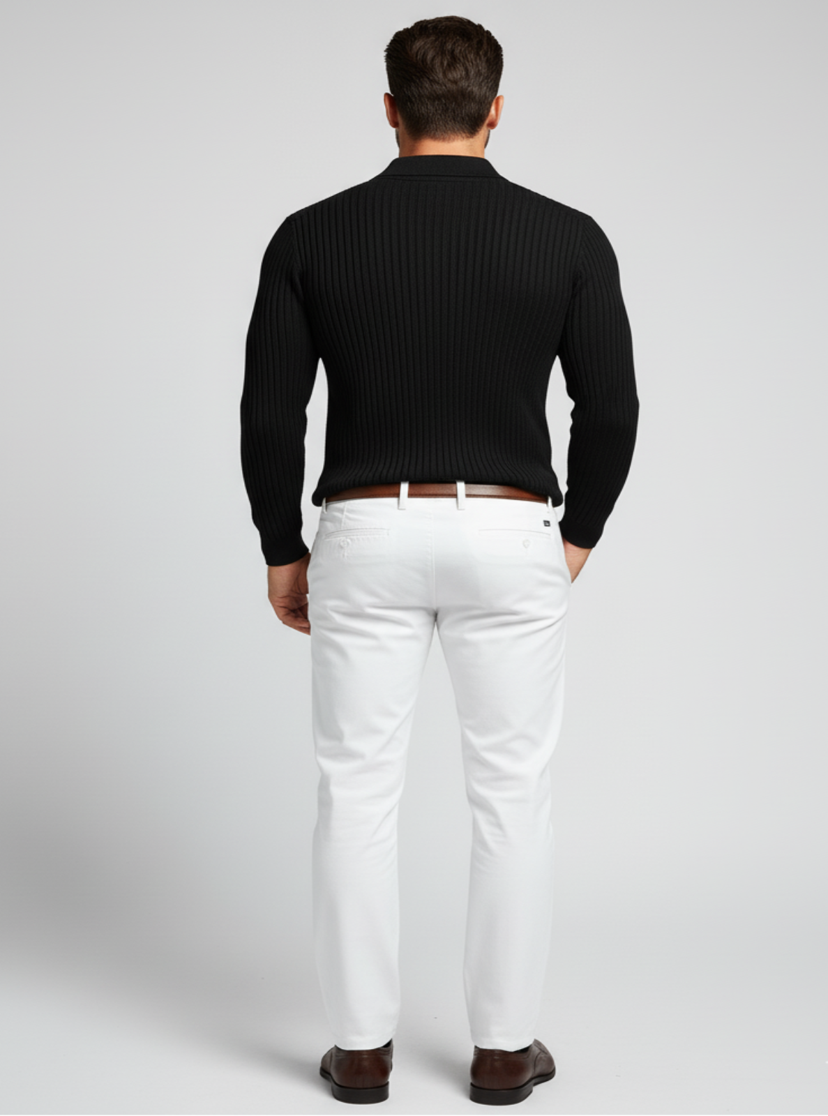 Man wearing a black ribbed sweater and white pants on a light gray background