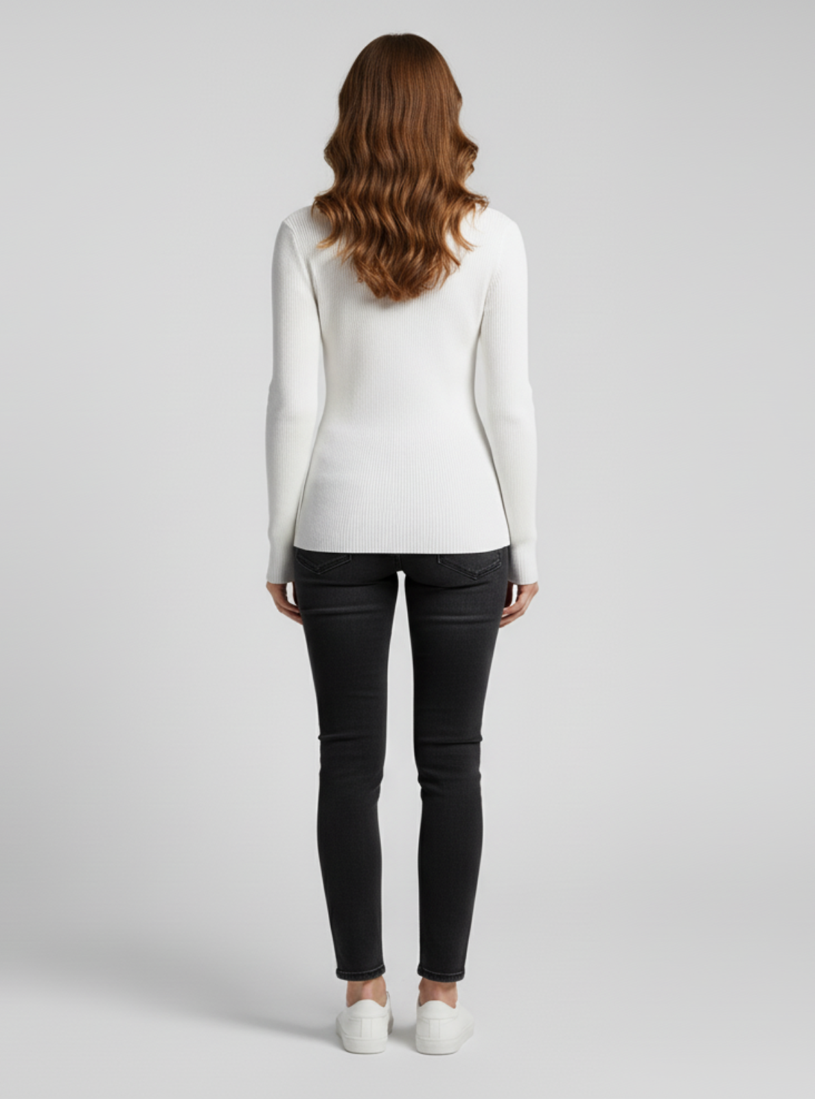 Woman wearing a white long-sleeve top and black pants on a light gray background