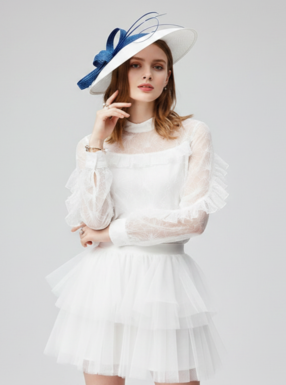 Woman wearing a white dress and blue hat with a bow on a gray background