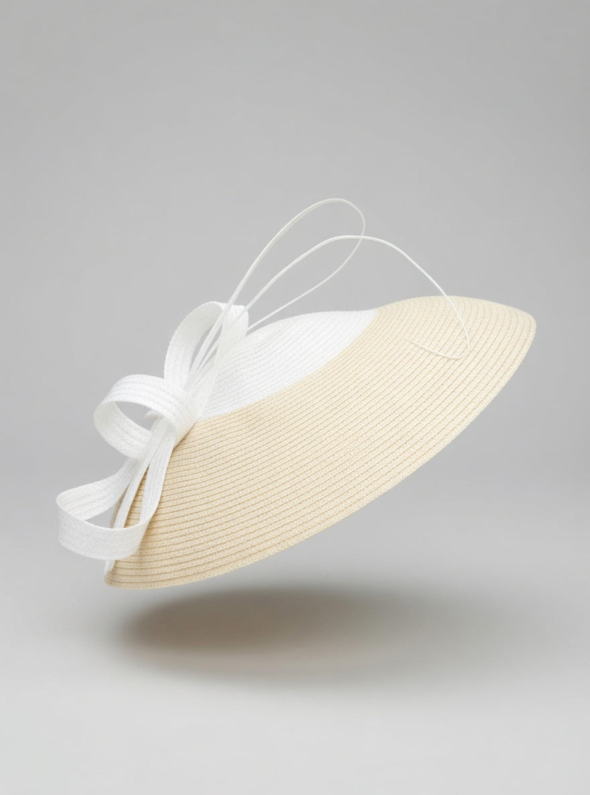 White and beige hat with a bow on a gray background