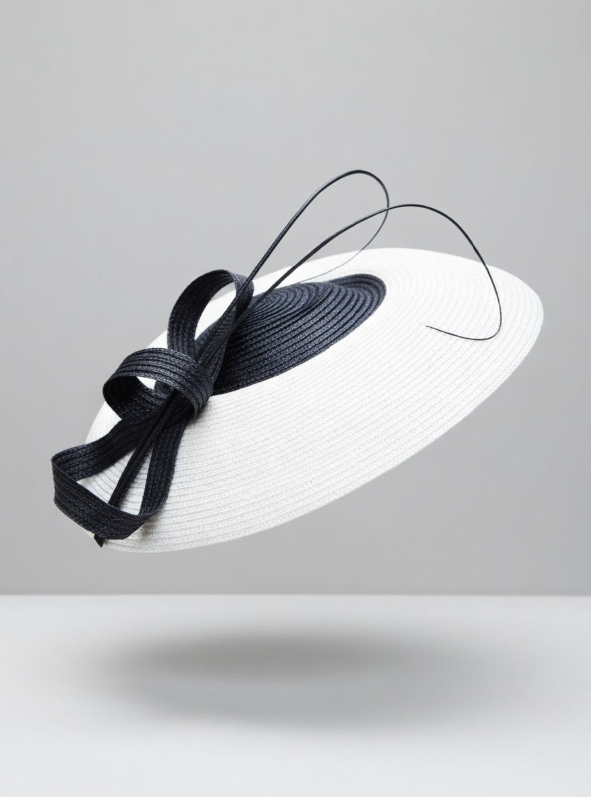 White hat with a black ribbon on a gray background