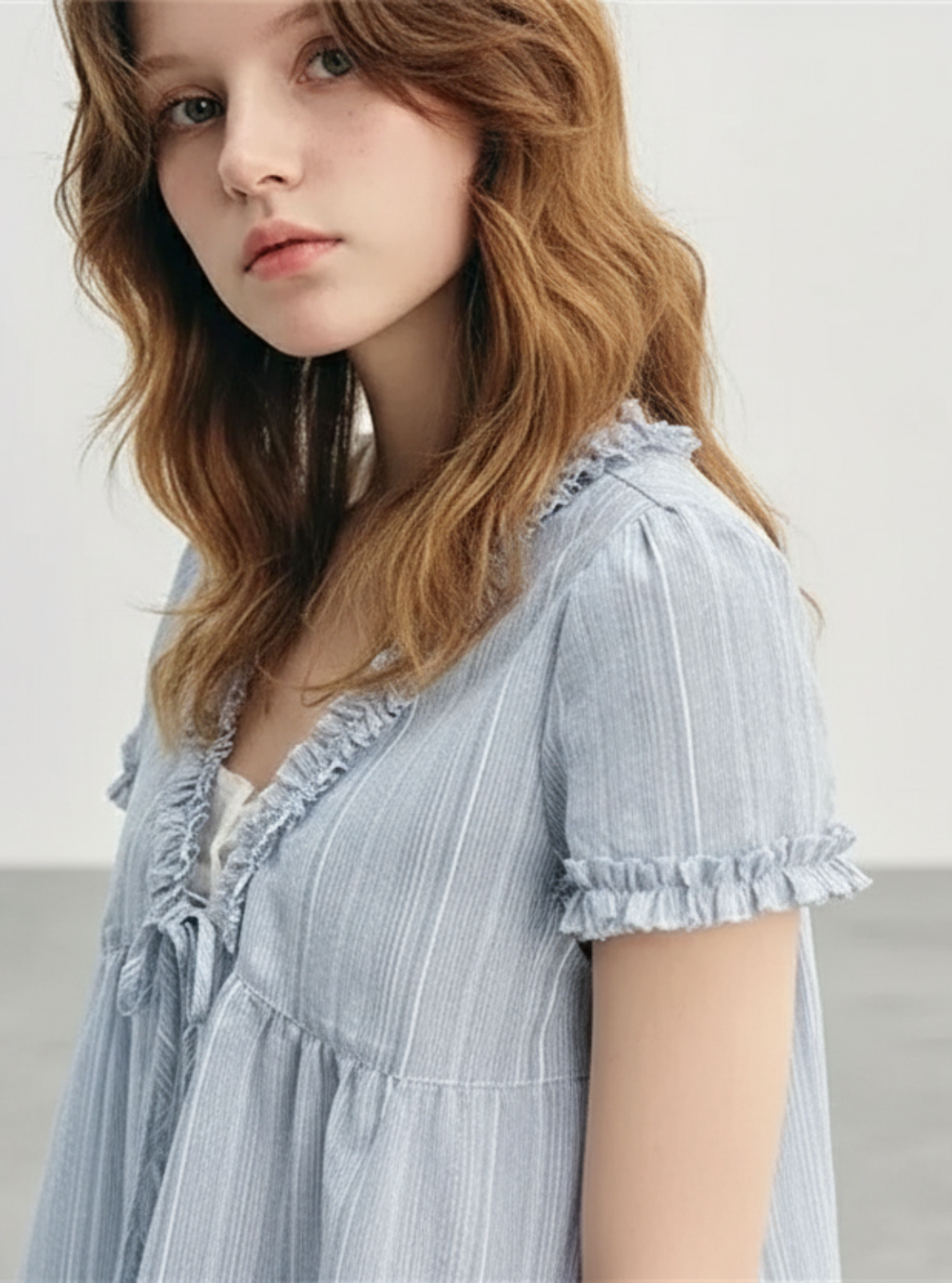Woman wearing a light blue dress with a plain background
