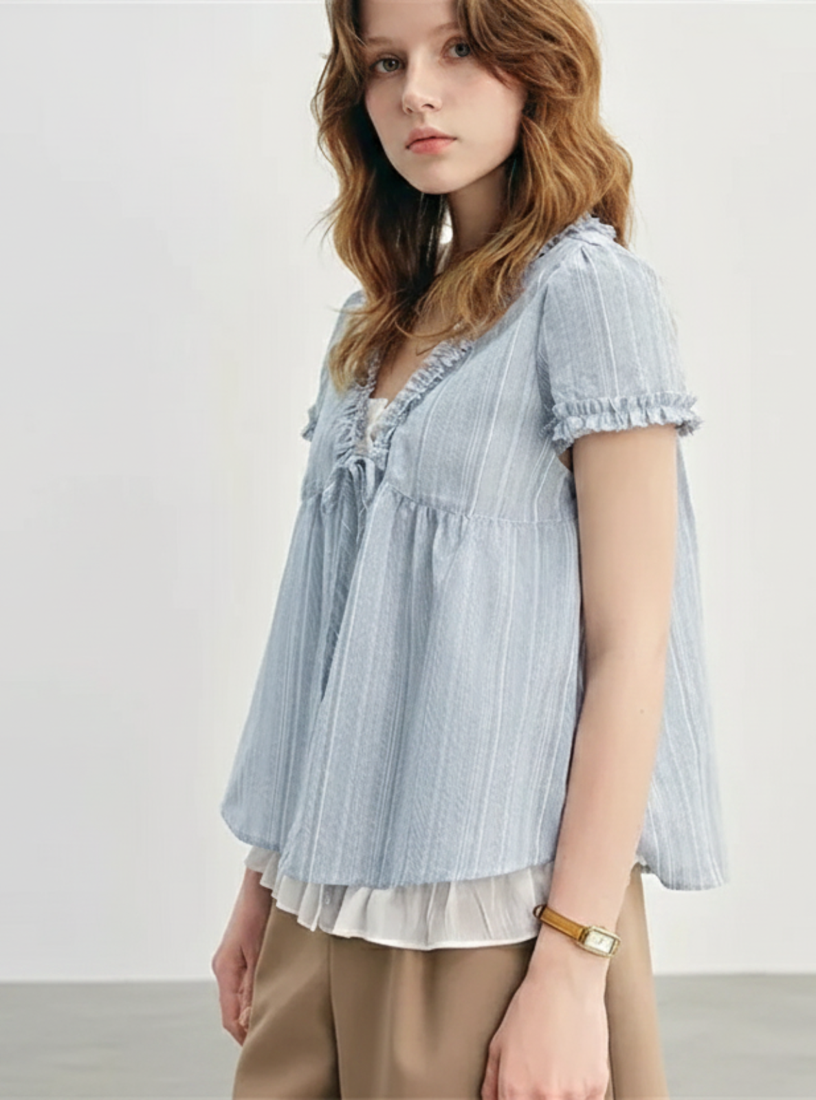 Woman wearing a light blue striped blouse with a plain background
