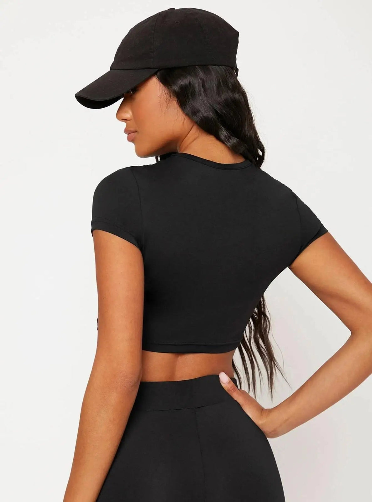 Person wearing a black crop top and cap on a white background