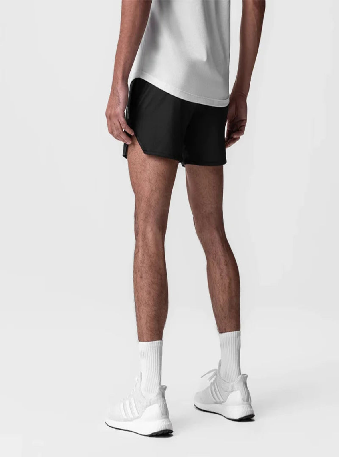 Person wearing black shorts, white socks, and white sneakers on a light gray background