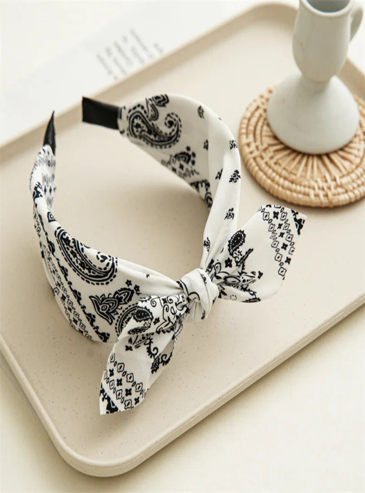 White headband with black paisley pattern on a beige tray