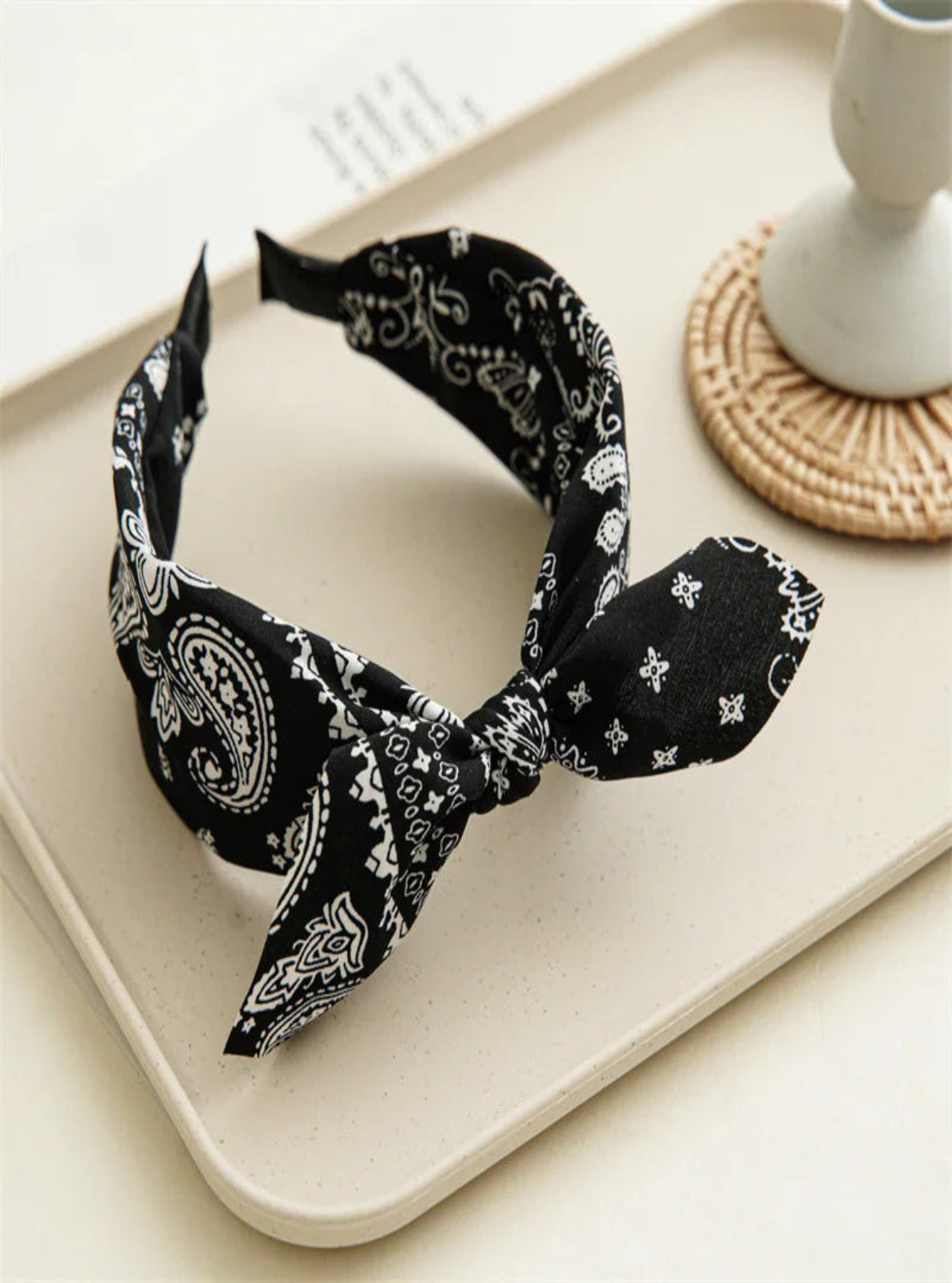 Black bandana headband with white patterns on a beige tray.