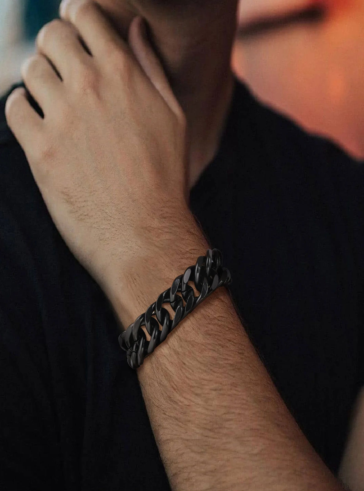 Person wearing a black chain bracelet on a blurred background