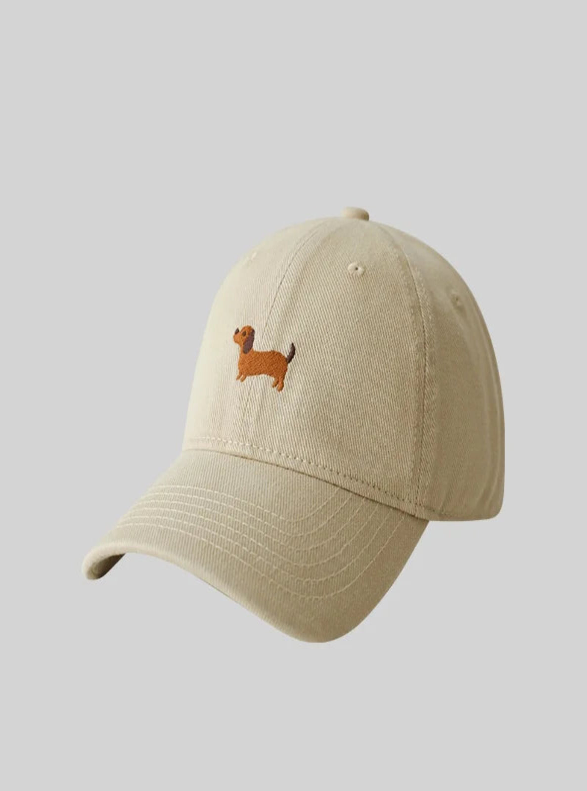 Beige cap with a small embroidered dog design on a light gray background