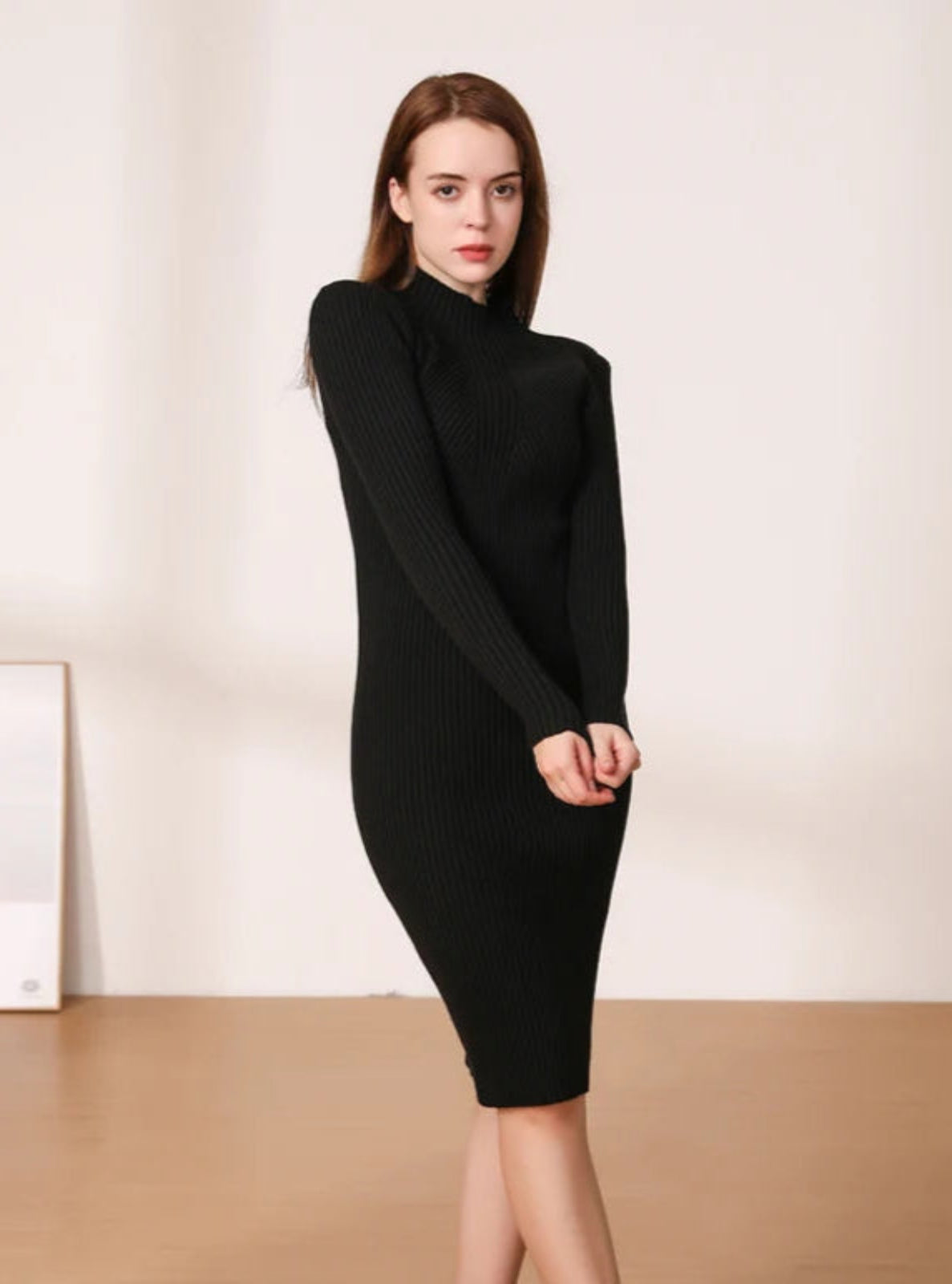 Woman wearing a black ribbed dress against a plain background