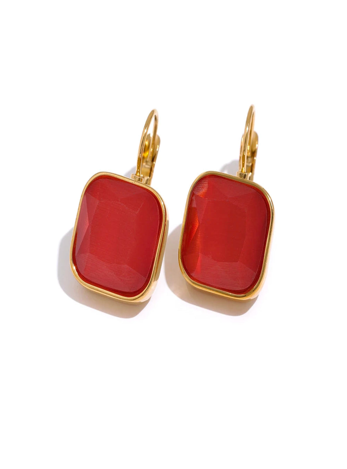 Gold earrings with red square stones on a white background
