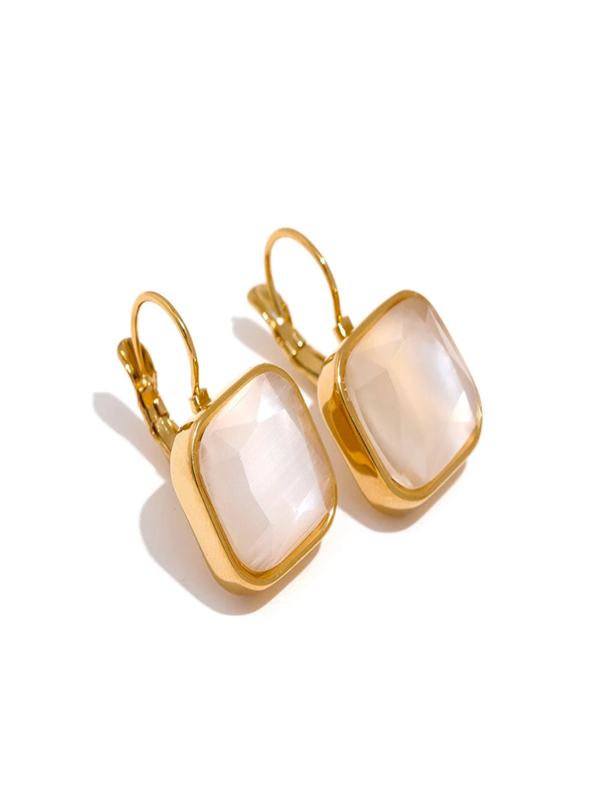 Gold earrings with square white stones on a white background