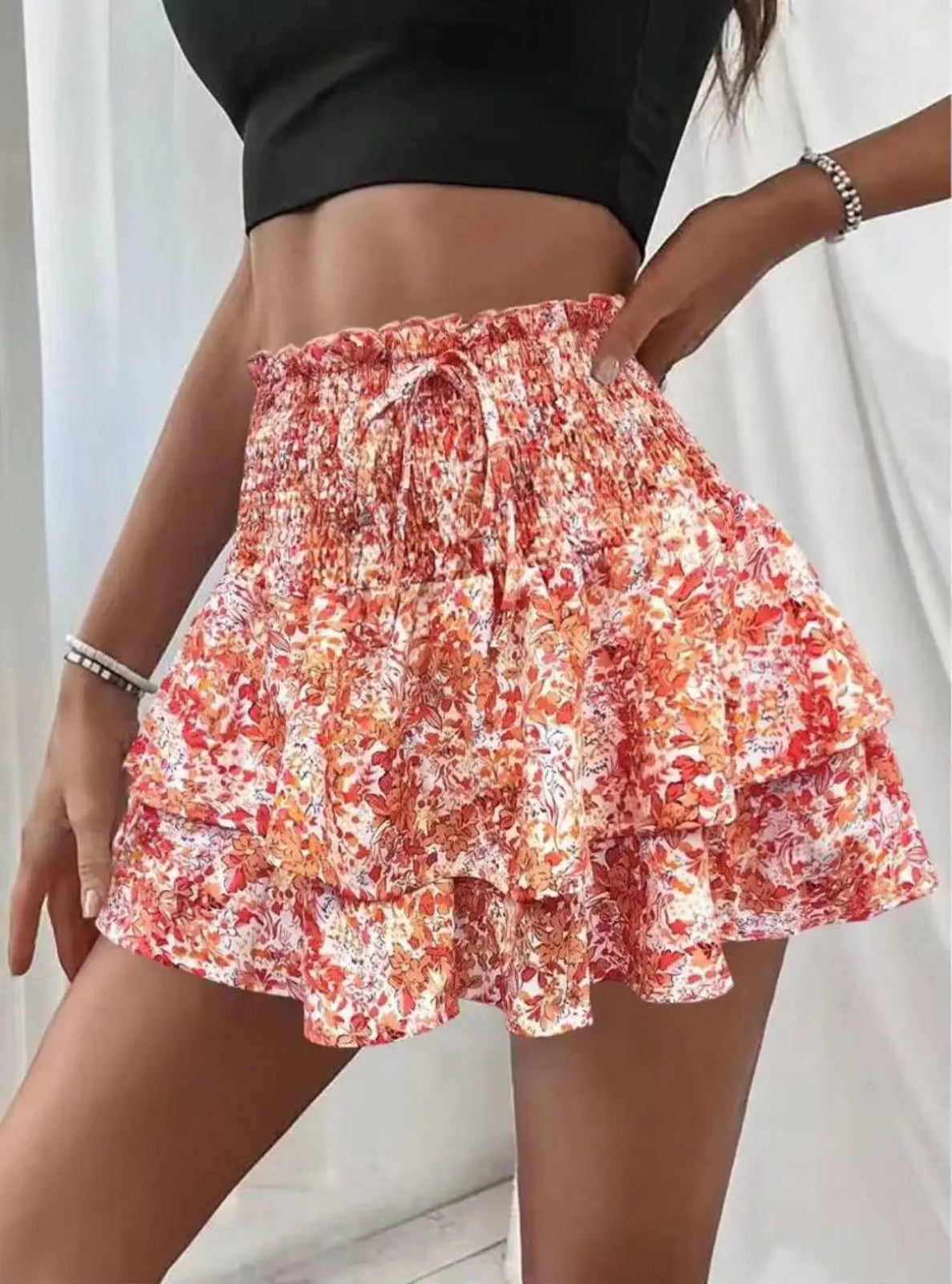 Person wearing a floral tiered shorts with a plain background