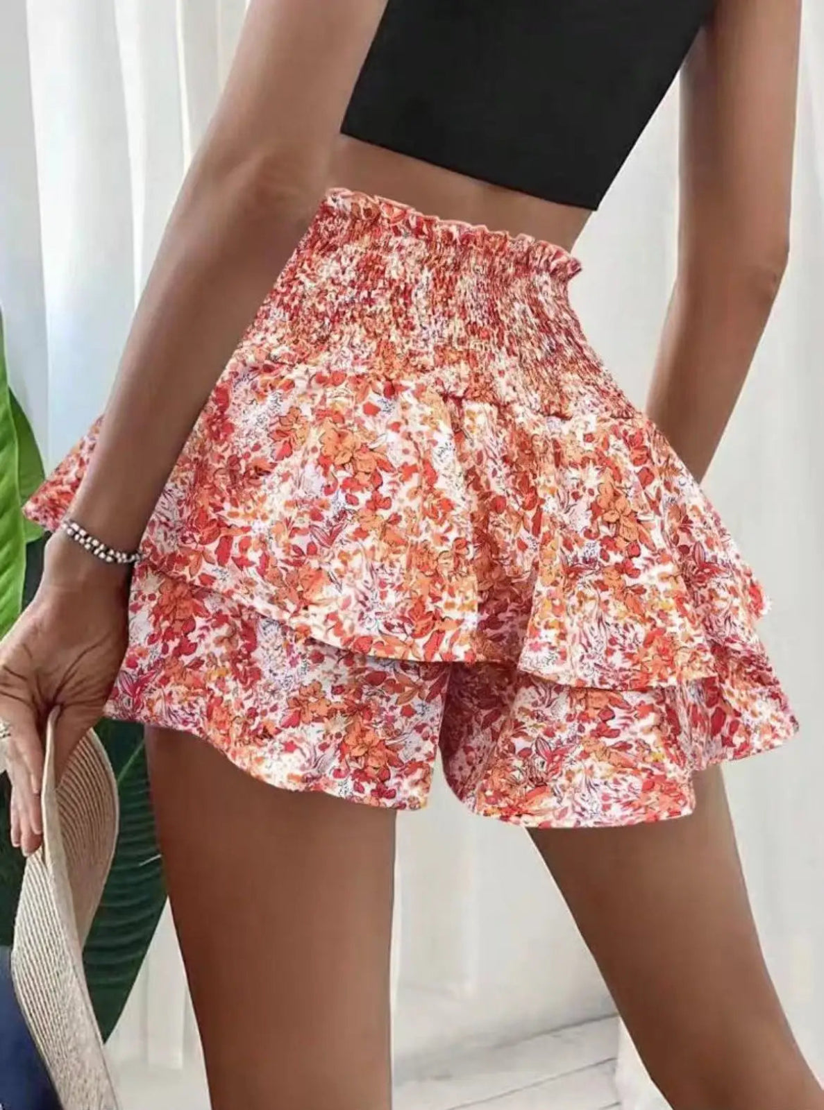 Person wearing a floral tiered shorts with a plain background