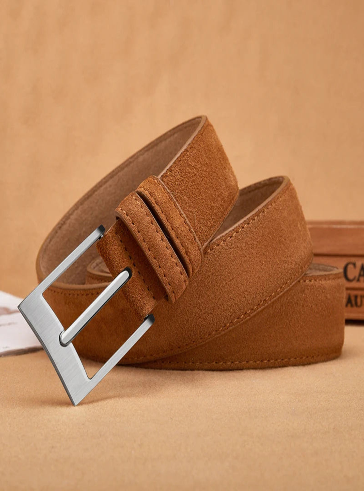 Brown suede belt with a silver buckle on a beige background
