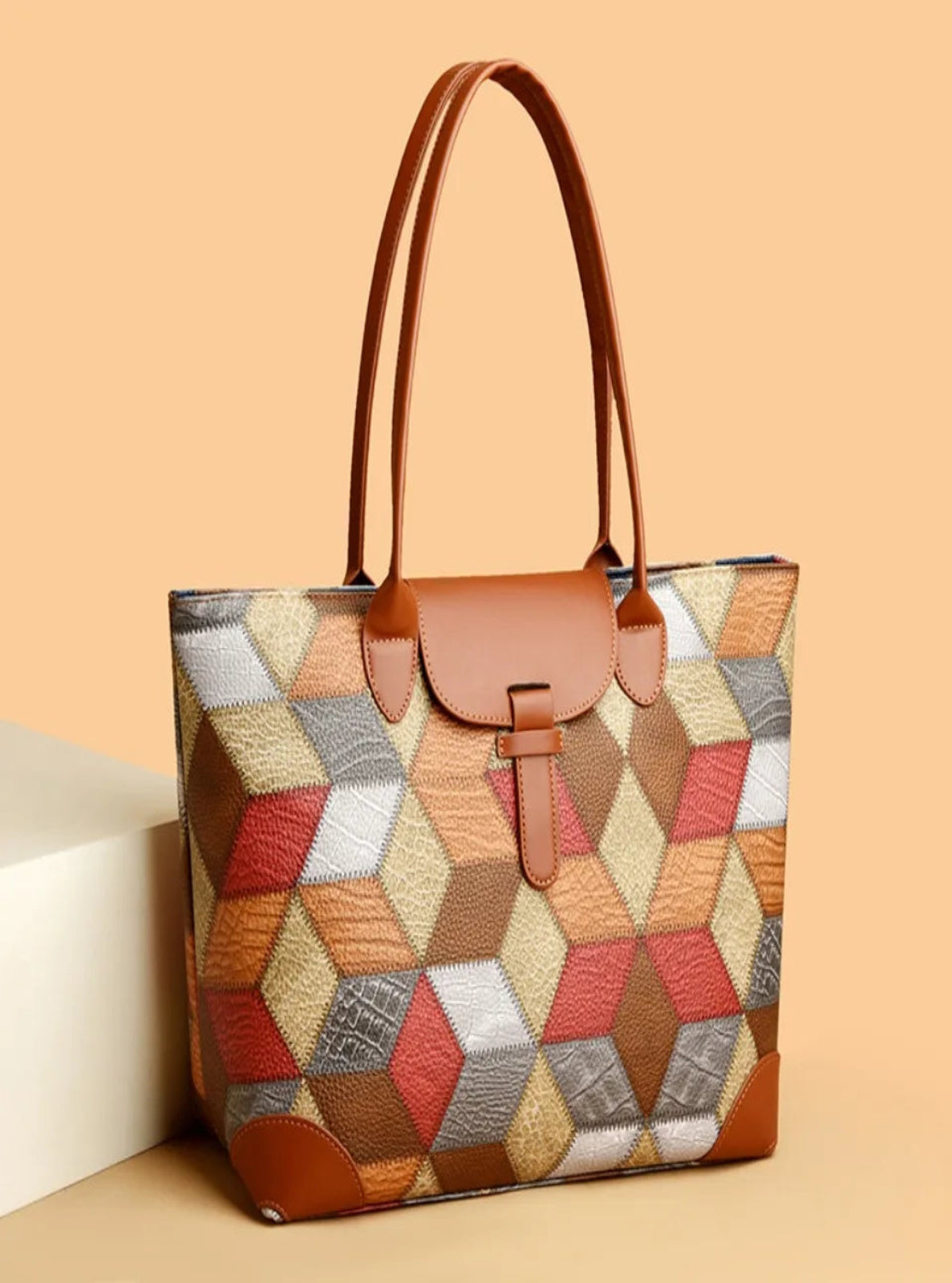 Multicolored geometric patterned handbag with brown leather accents on a beige background