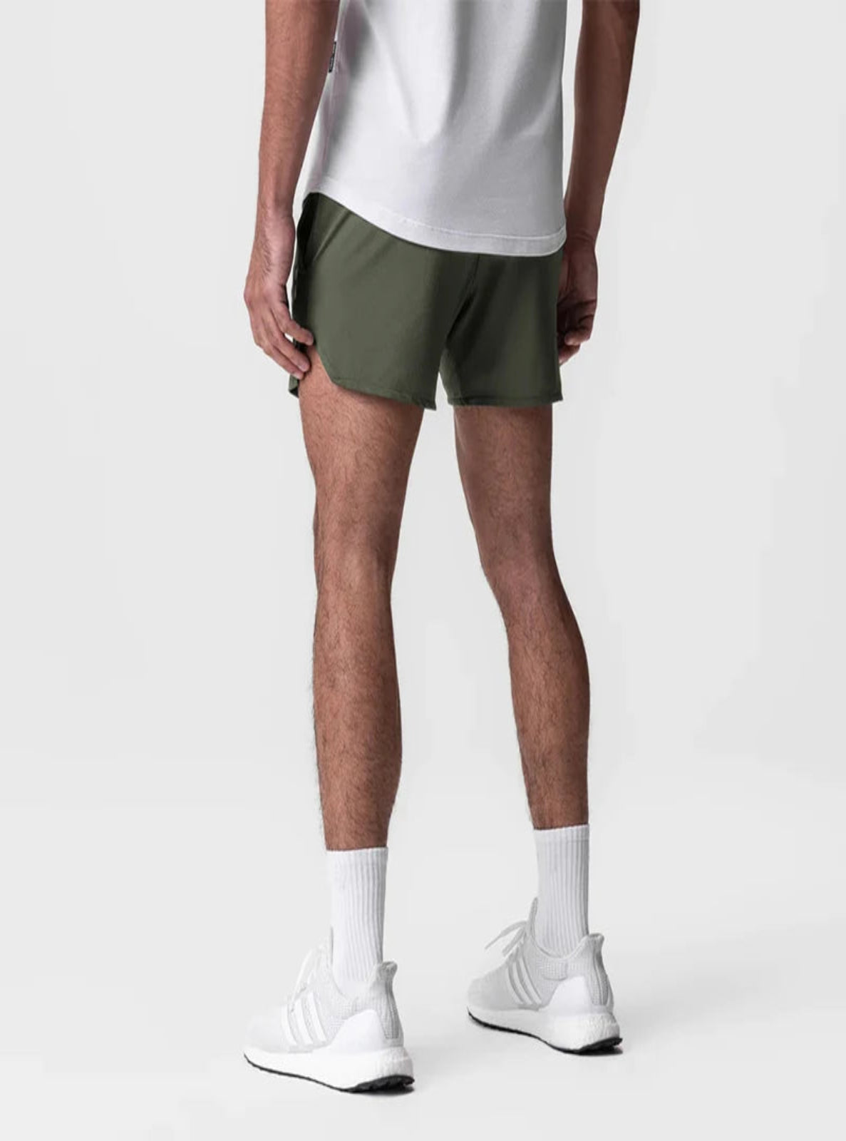 Person wearing green shorts and white sneakers on a plain background