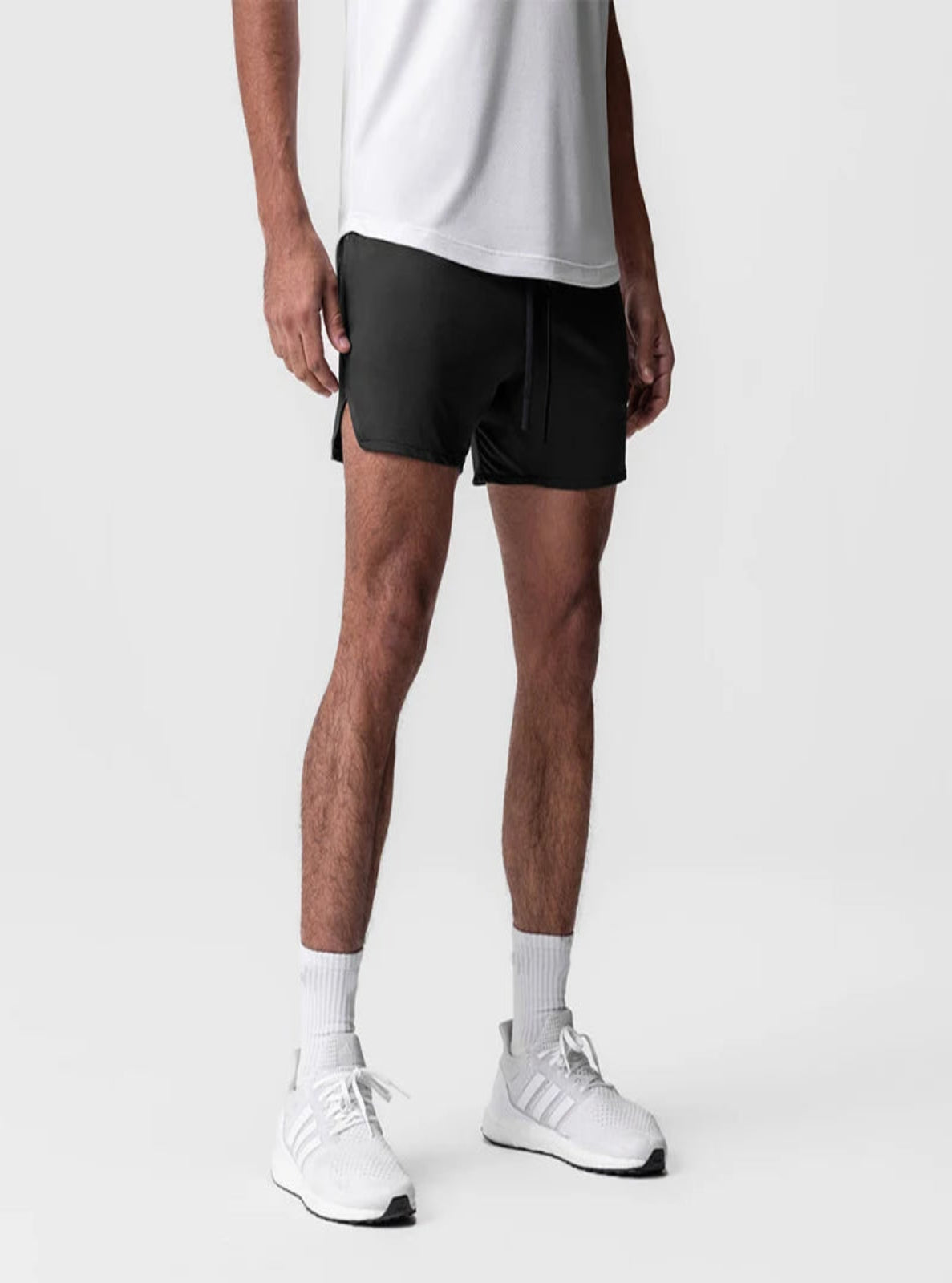 Person wearing black shorts, white socks, and white sneakers on a light gray background