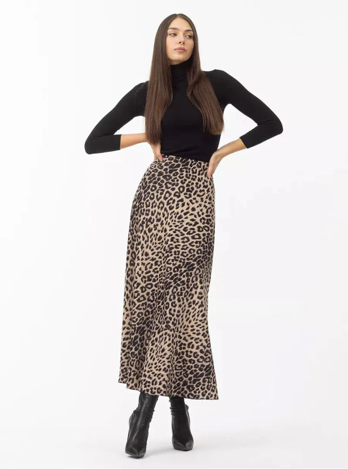 Woman wearing a black long-sleeve top and leopard print skirt on a white background