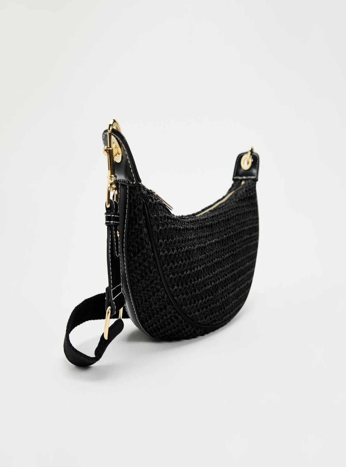 Black woven handbag with gold accents on a light gray background