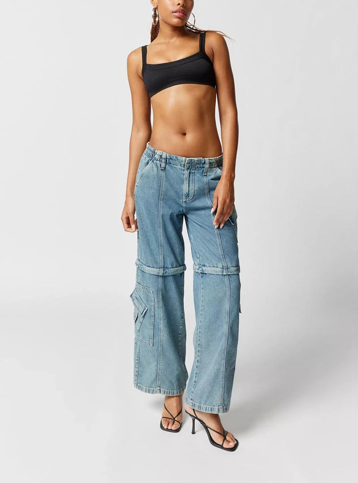Person wearing a black crop top and blue denim wide-leg pants on a white background