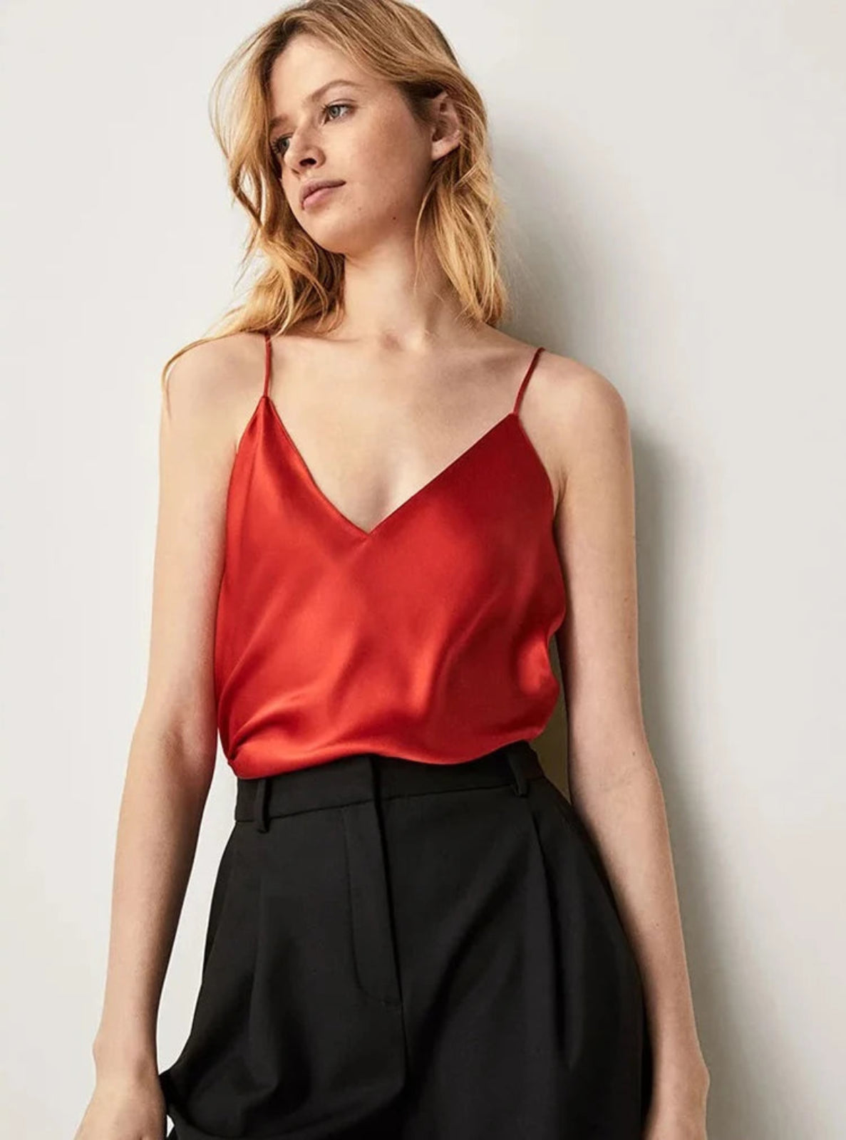 Woman wearing a red top and black pants against a light background
