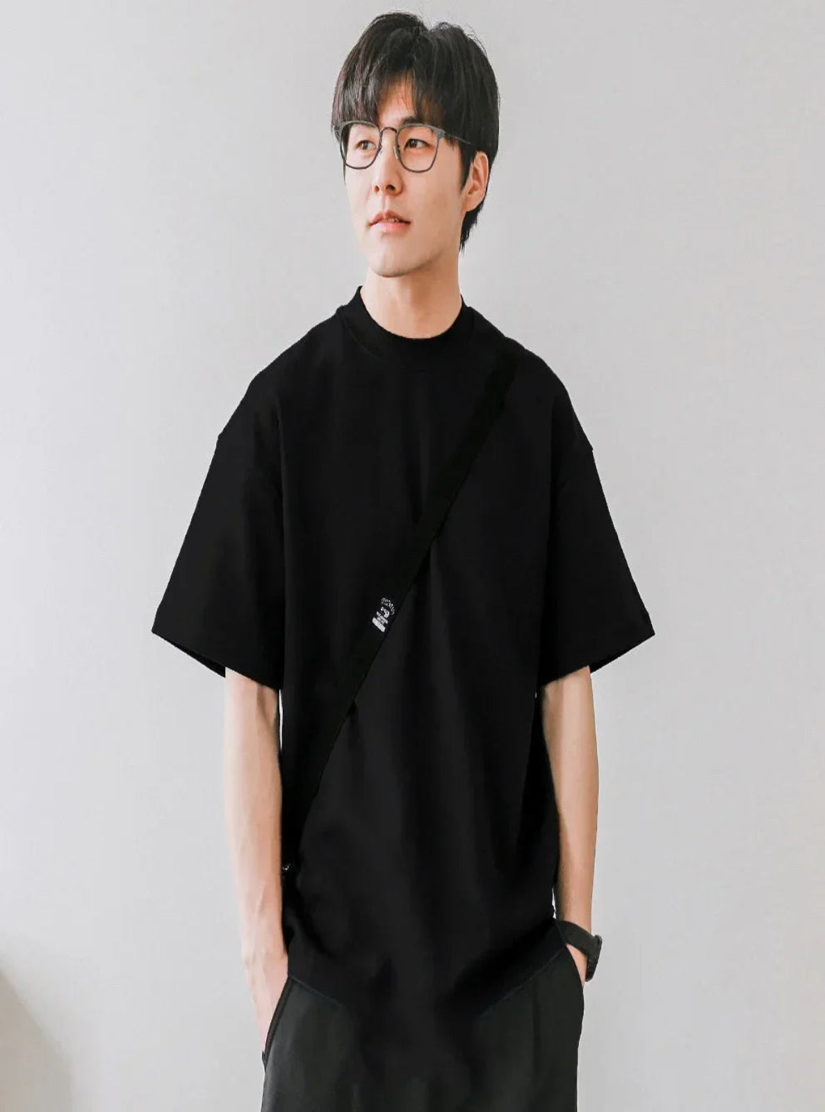 Person wearing a black t-shirt and pants against a plain background