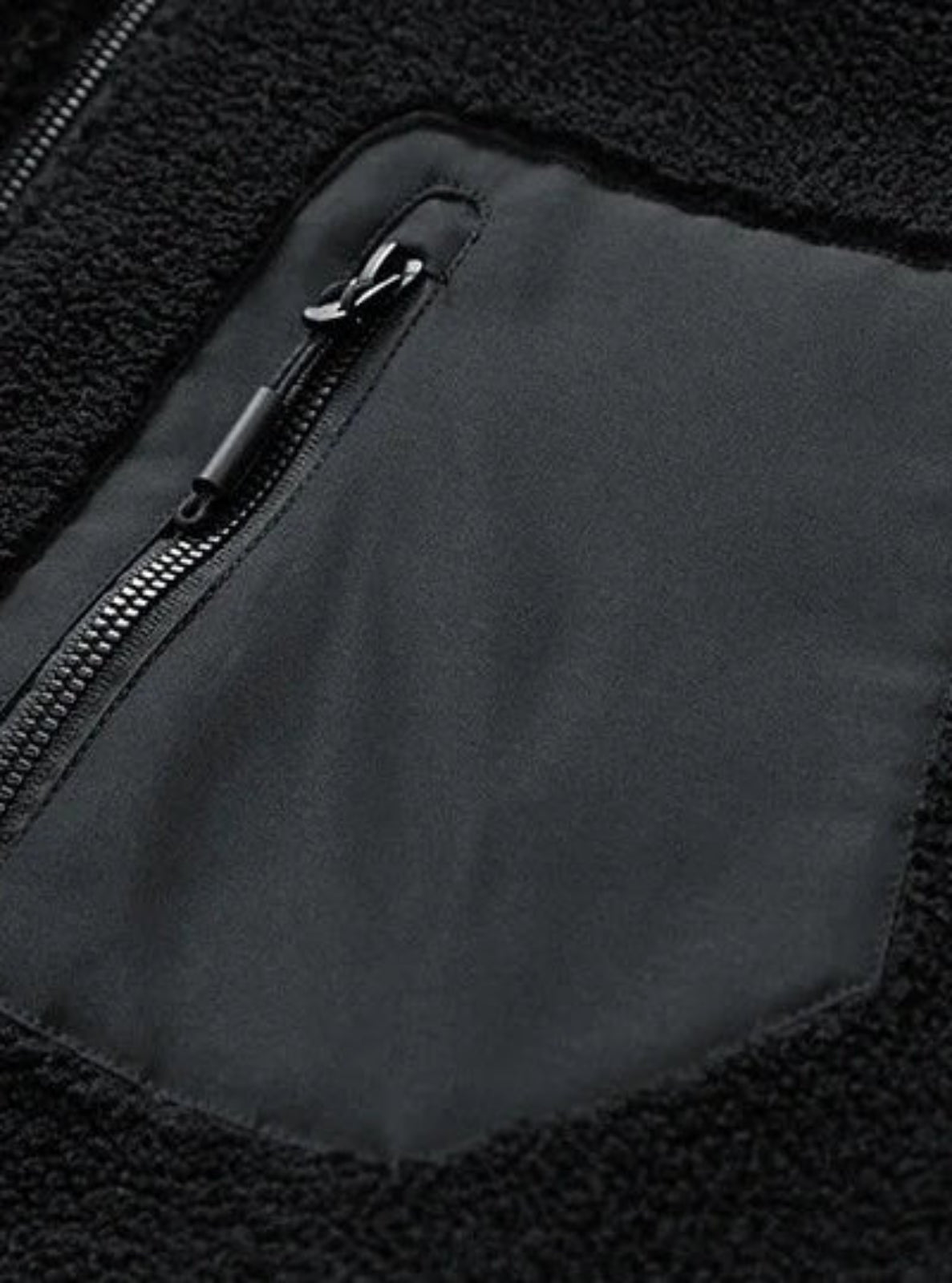 Close-up of a black fleece jacket with a zipper pocket