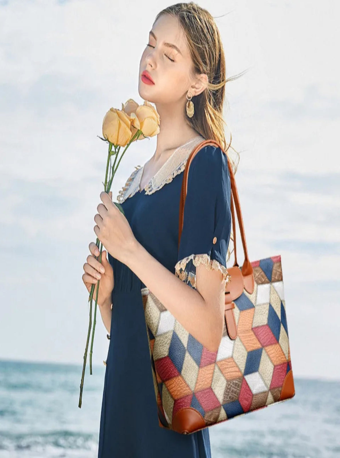 Woman holding a colorful patterned handbag and flowers by the ocean