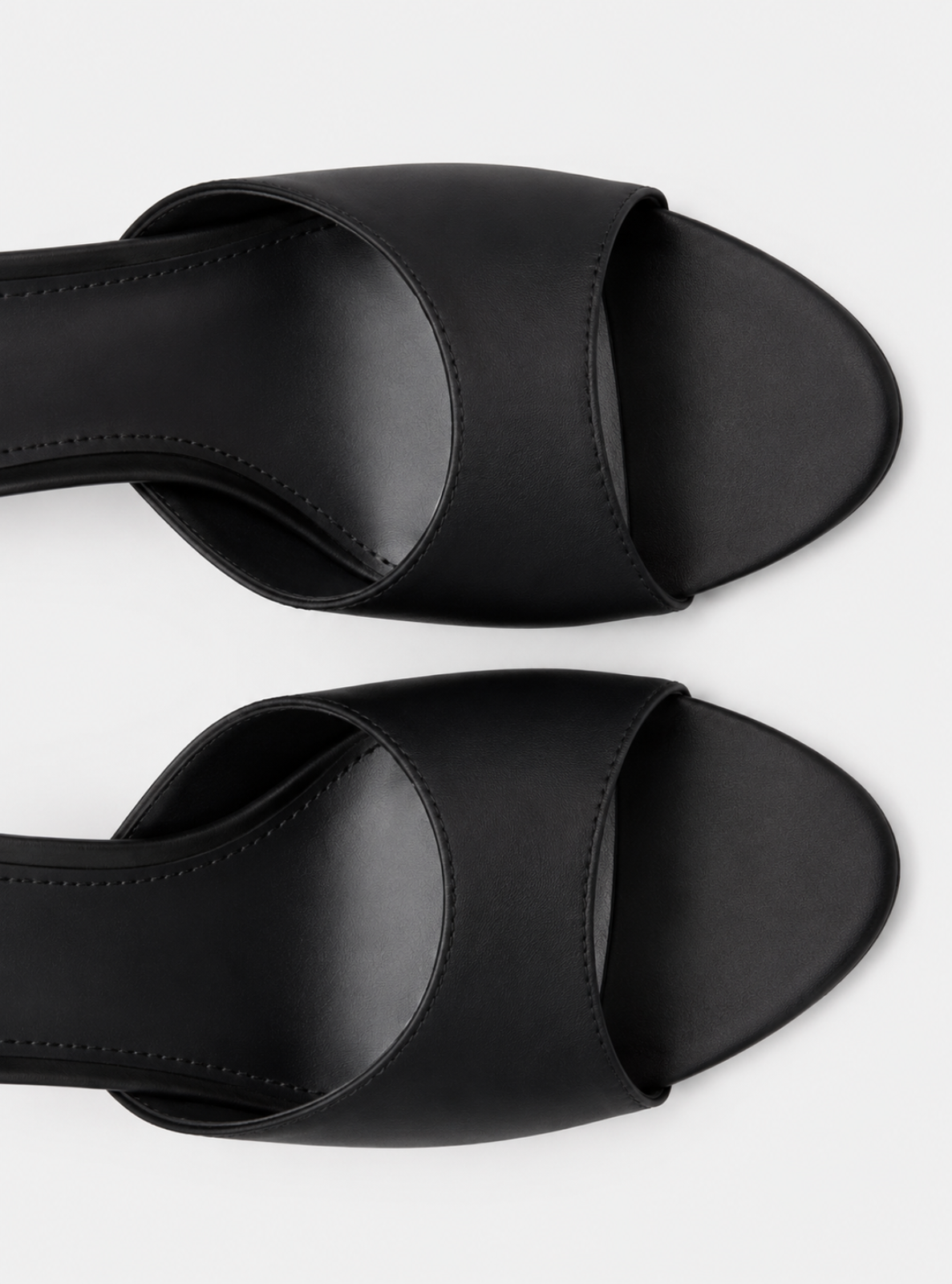Black leather slide sandals with wide crisscross straps and low block heels, shown from a top-down angle on a light gray background.