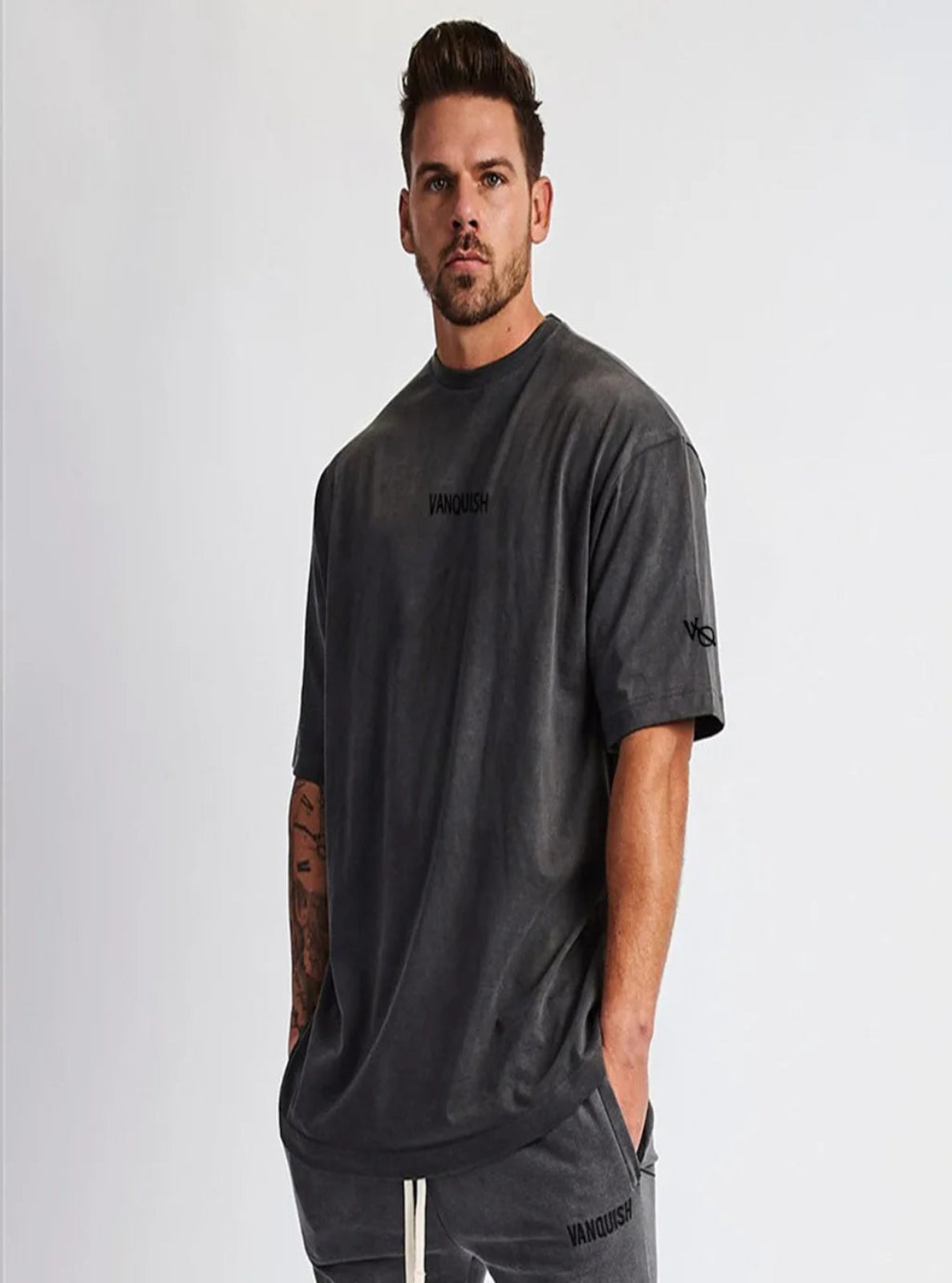 Man wearing a dark gray t-shirt with 'Vanguard' branding on a light gray background