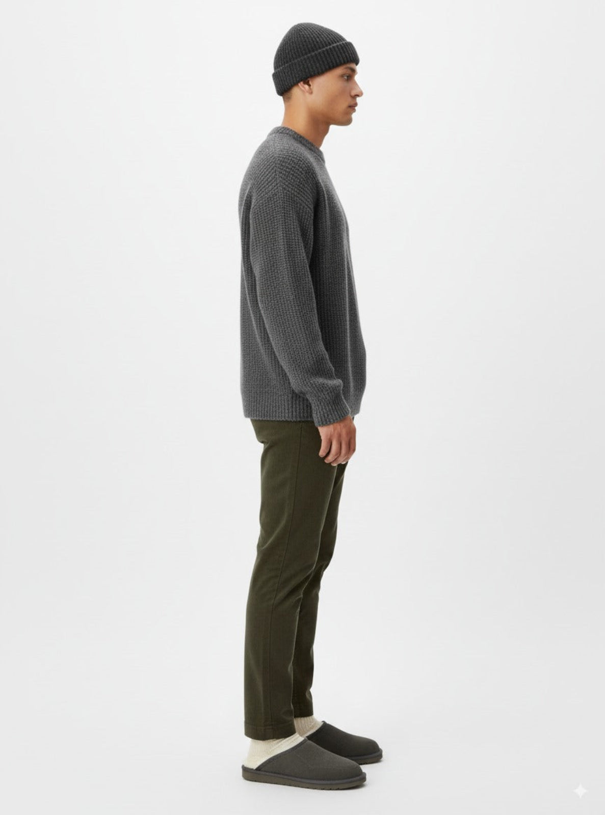 Man wearing a gray sweater, black beanie, and green pants on a white background