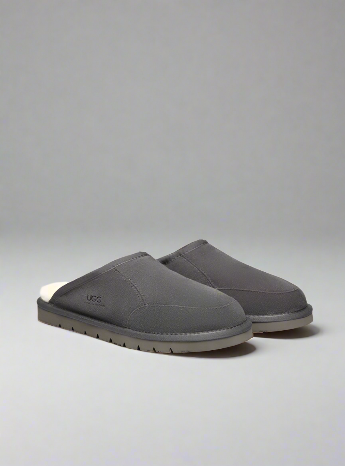 Pair of gray UGG slippers on a light gray background