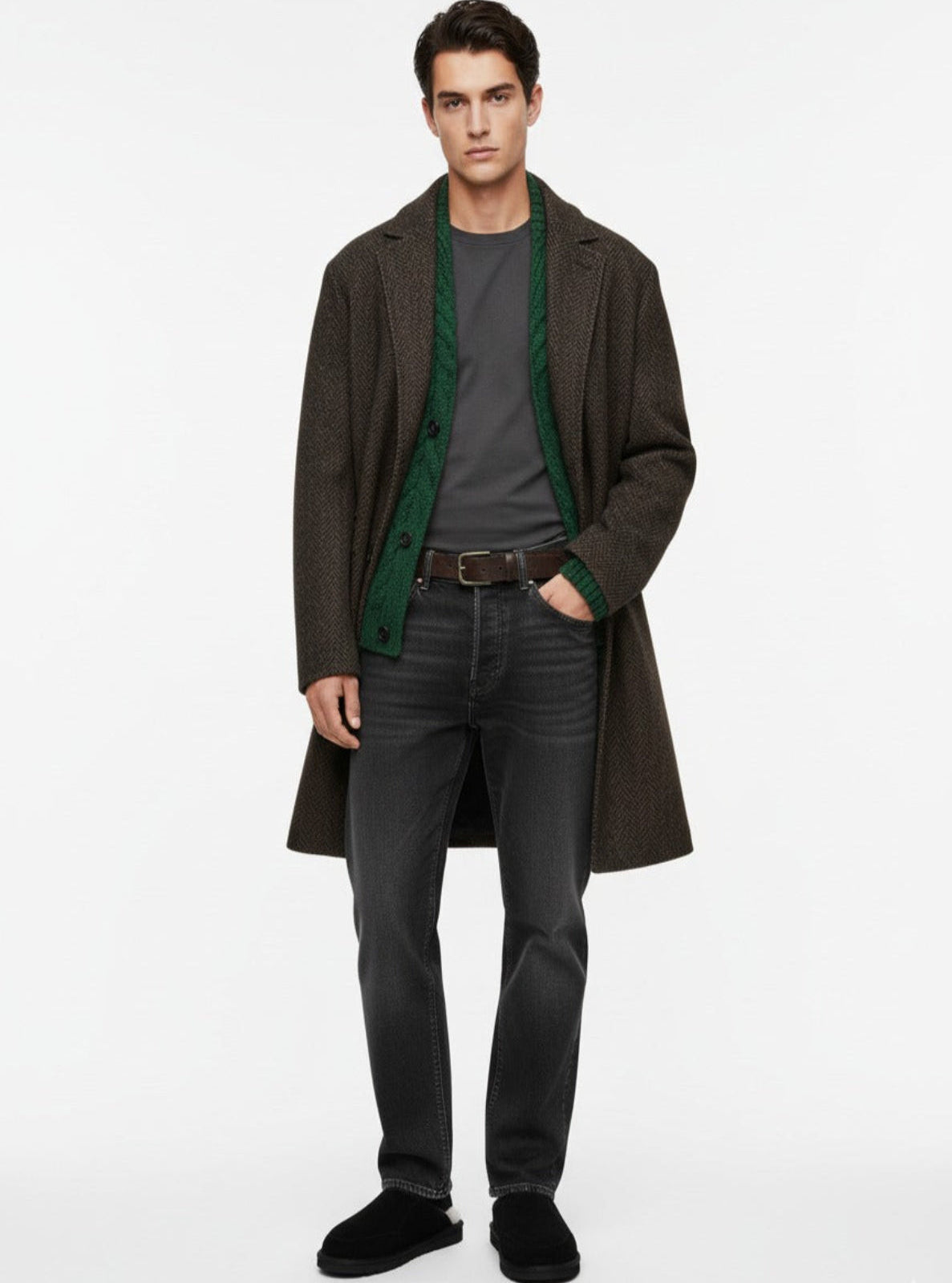 Man wearing a dark coat with green lining, gray shirt, and black pants on a white background