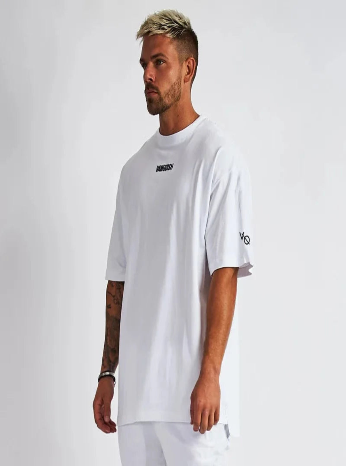 Man wearing a white t-shirt with brand logos on a plain background