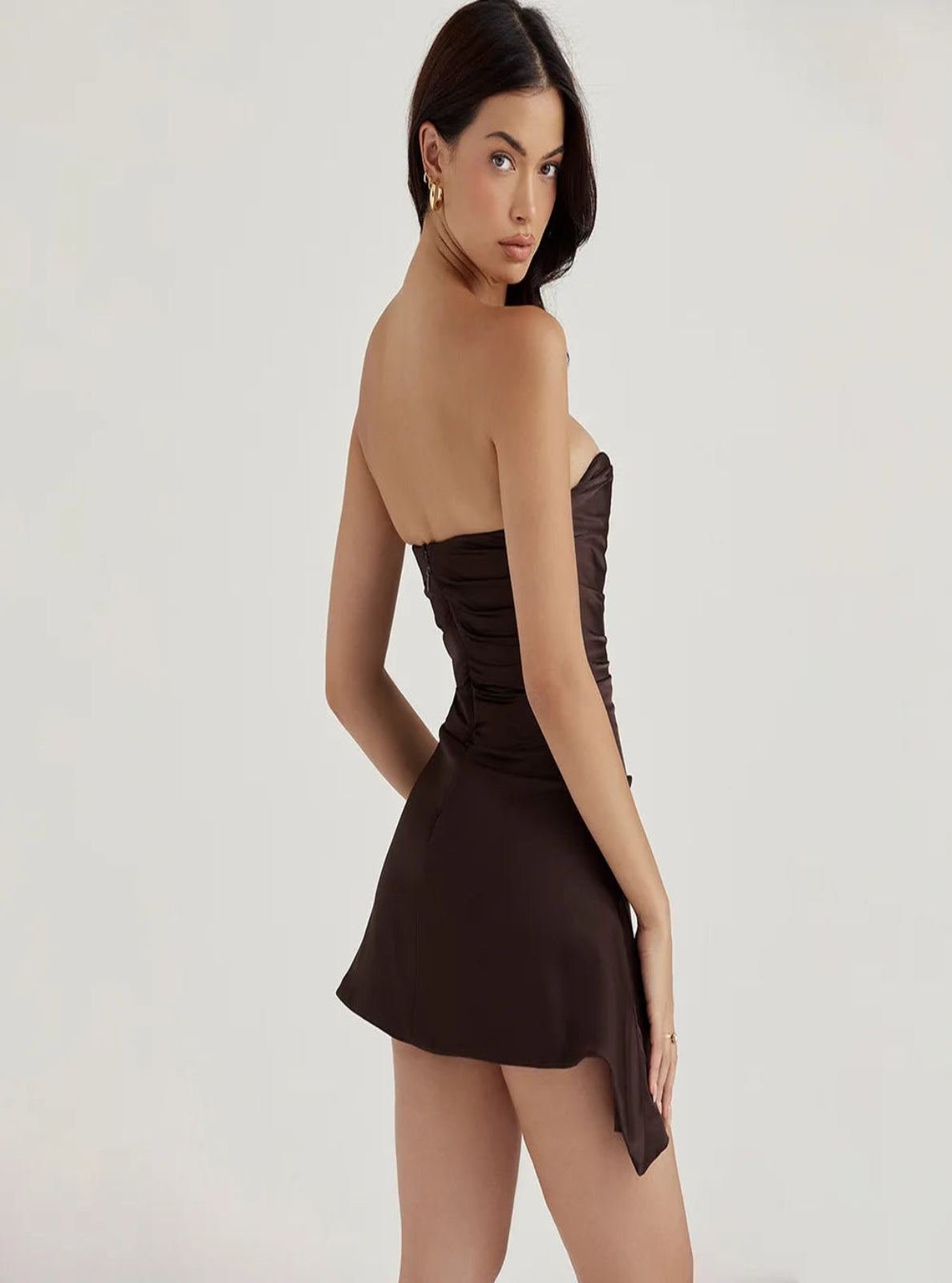 Woman wearing a brown strapless dress on a plain background