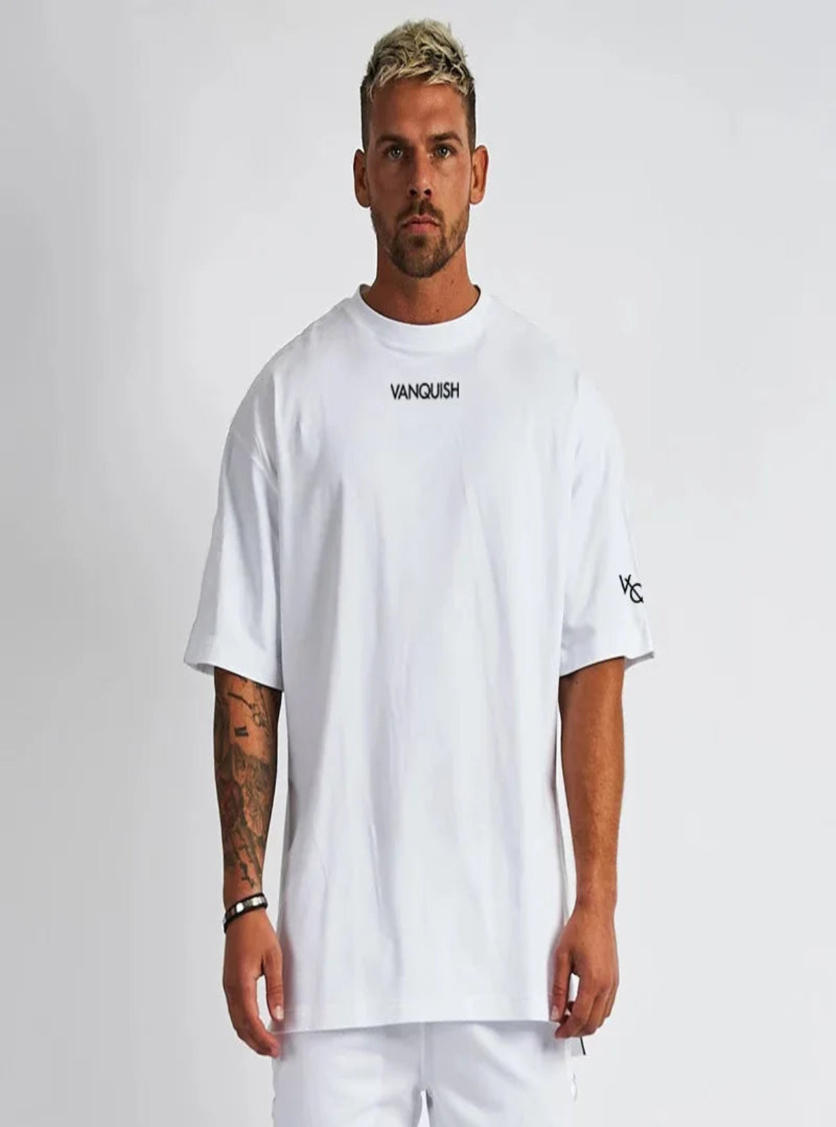 Man wearing a white 'Vanquish' t-shirt on a plain background
