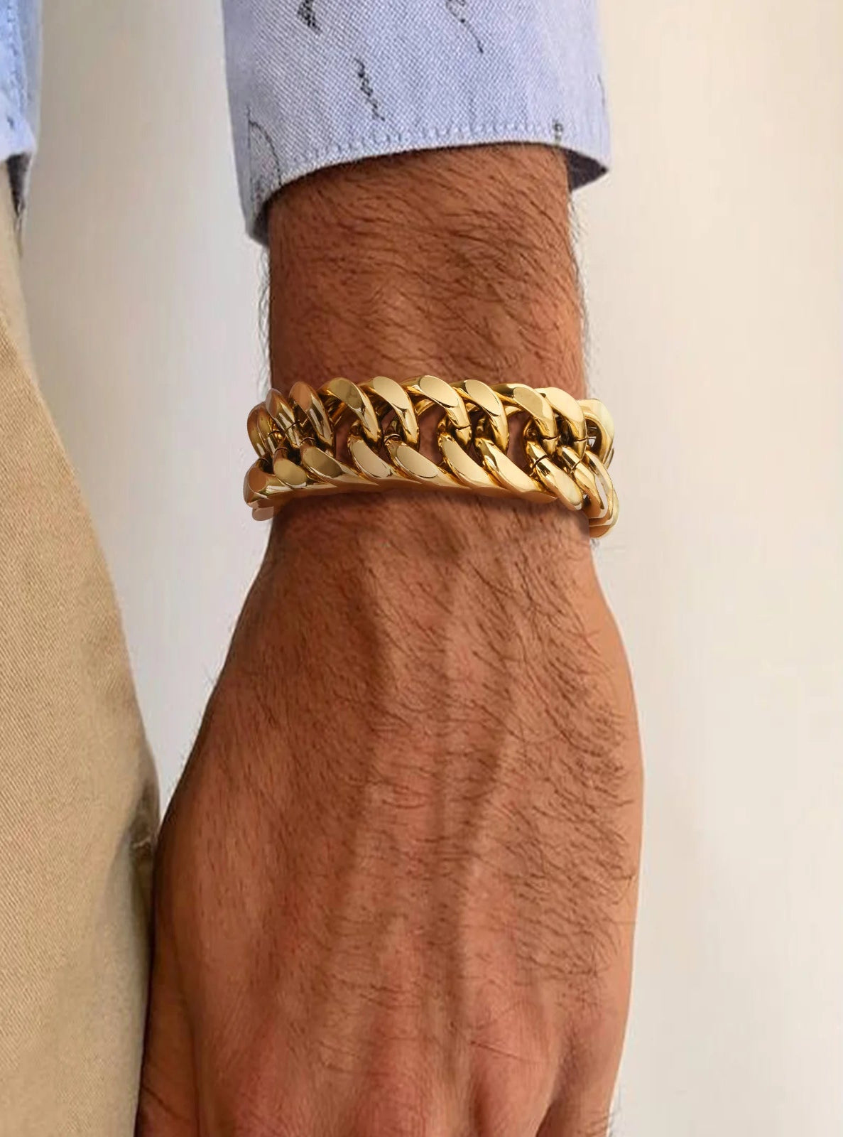 Gold chain bracelet on a wrist with a neutral background