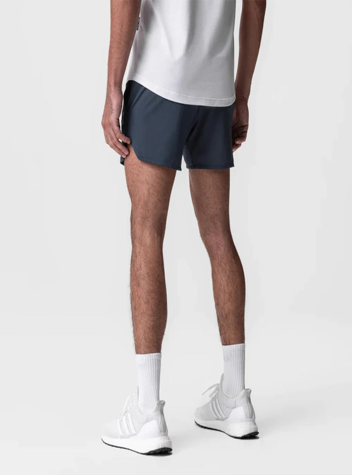 Person wearing navy shorts and white sneakers on a plain background