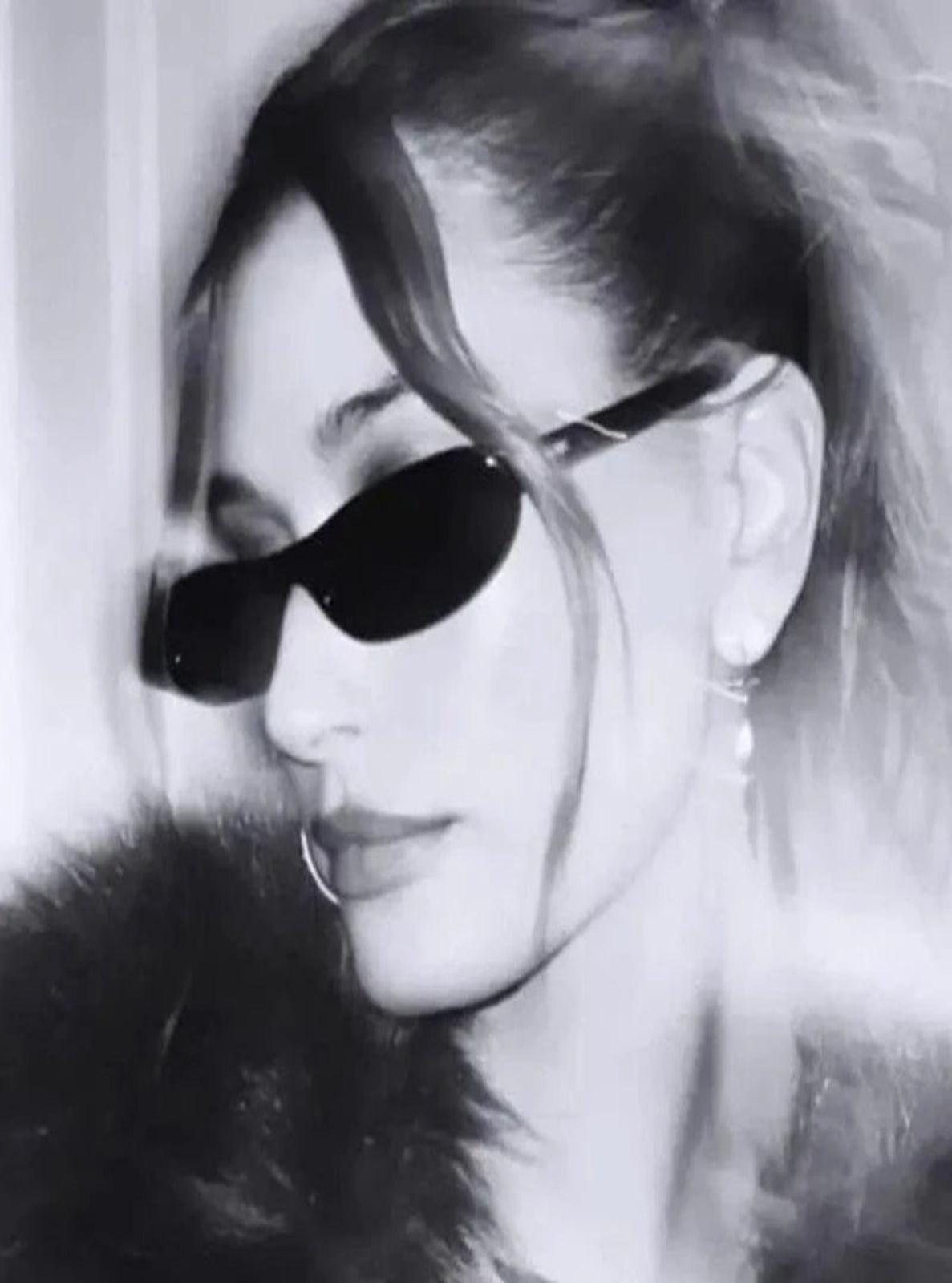 Black and white close-up of a person wearing sunglasses with a blurred background