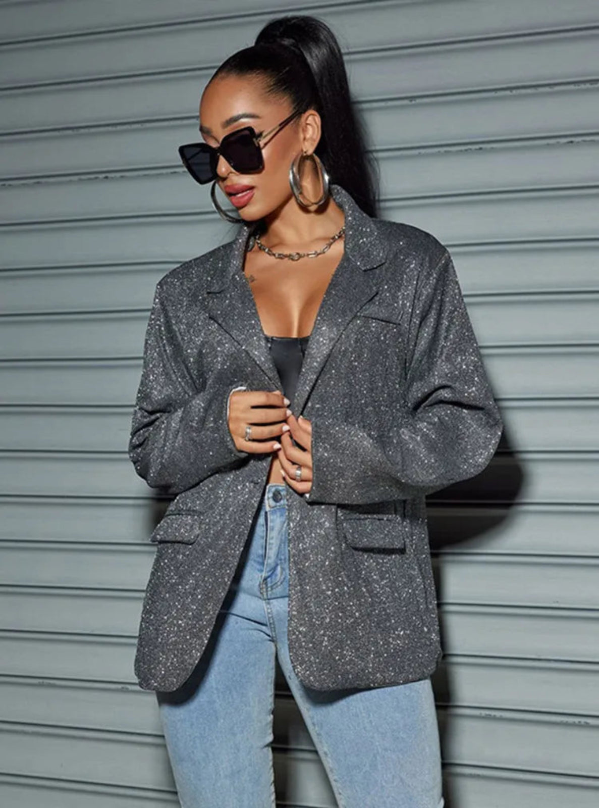 Woman wearing a gray blazer and blue jeans against a metallic background