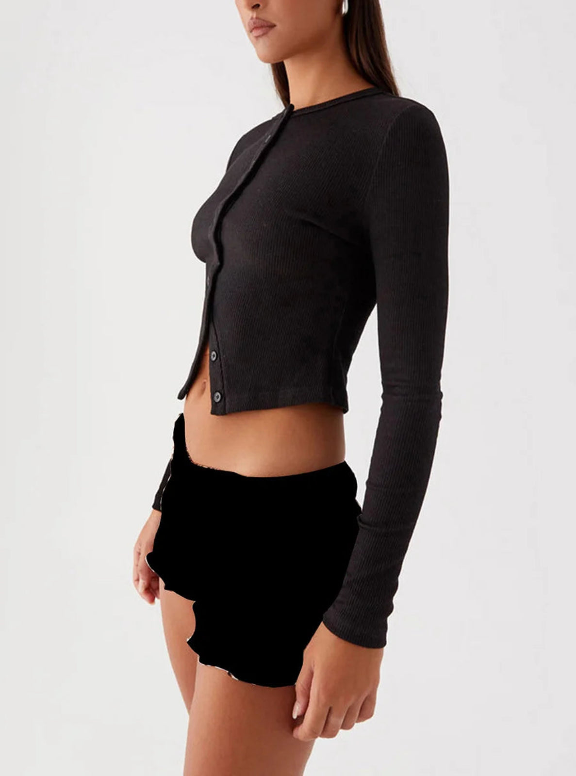 Person wearing a black cardigan and black shorts on a white background