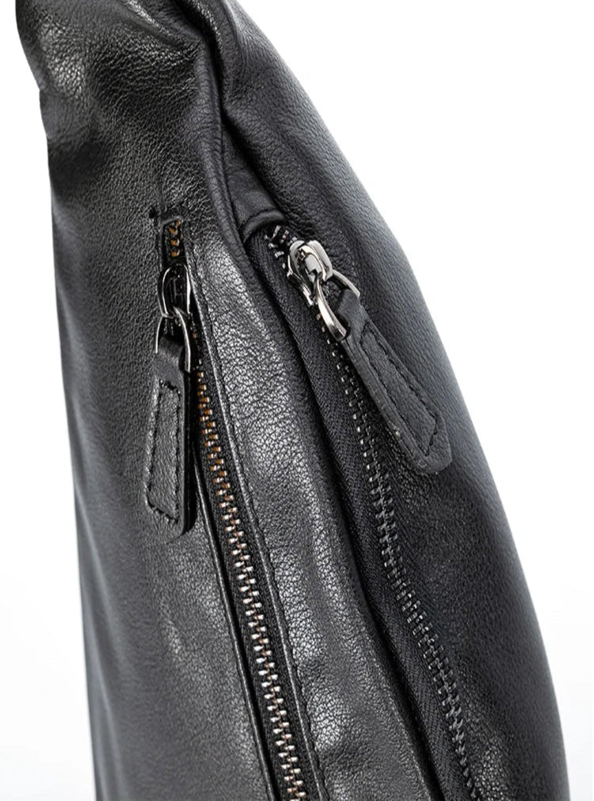 Close-up of a black leather bag with zippers on a white background