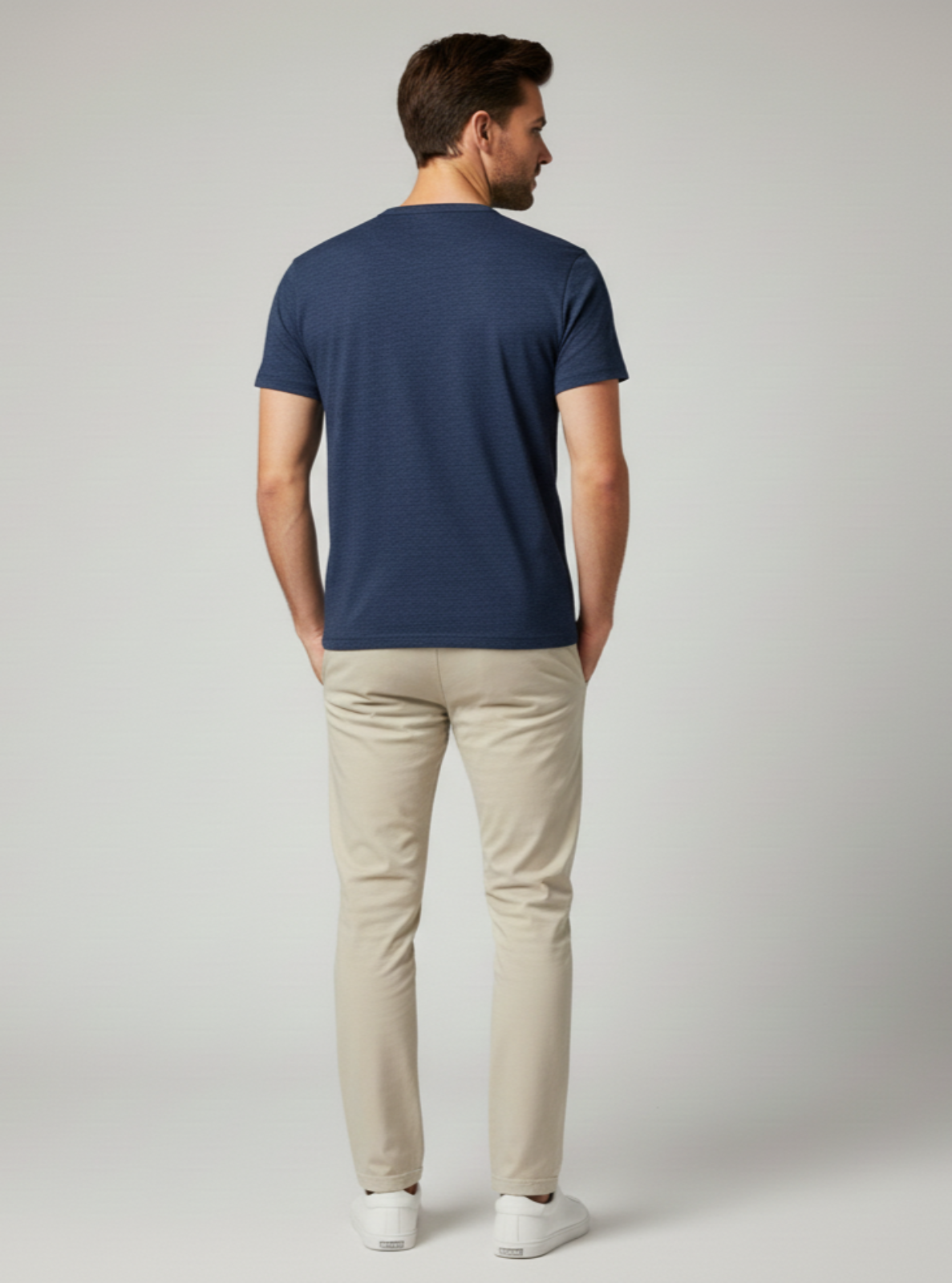 Man wearing a navy blue t-shirt and beige pants on a light gray background