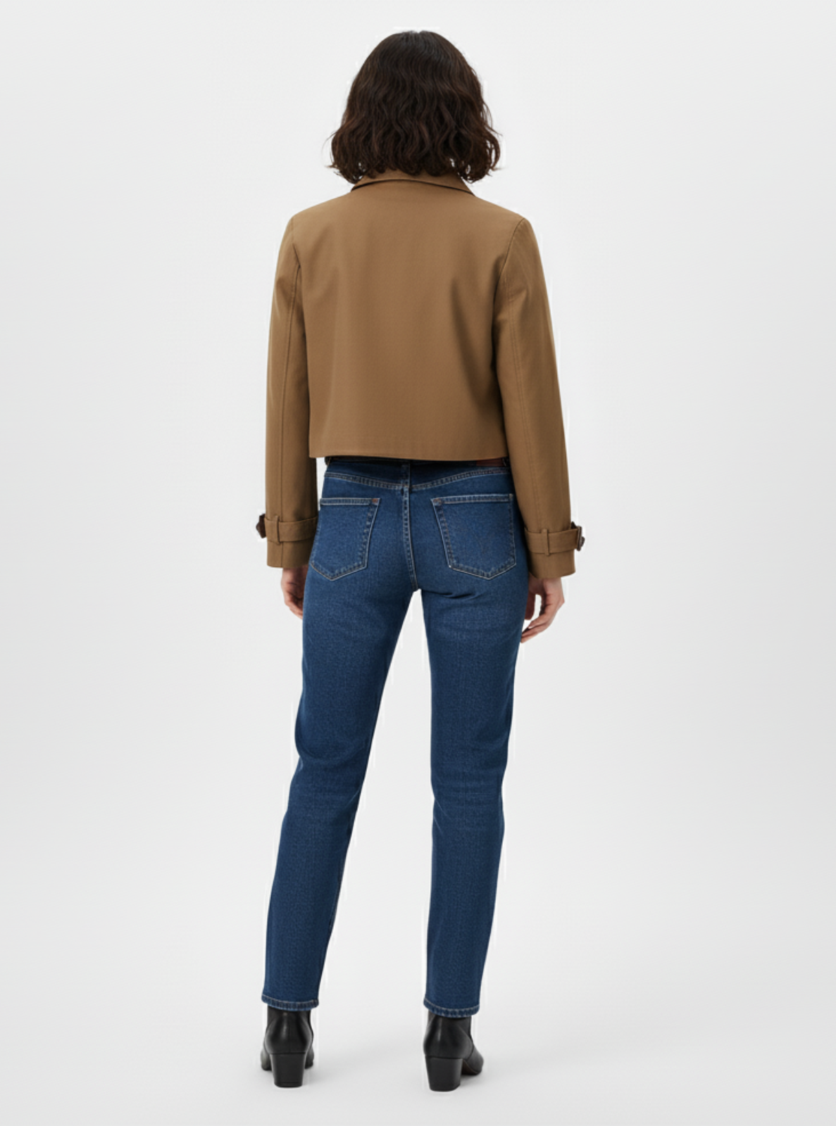 Person wearing a brown jacket and blue jeans on a white background