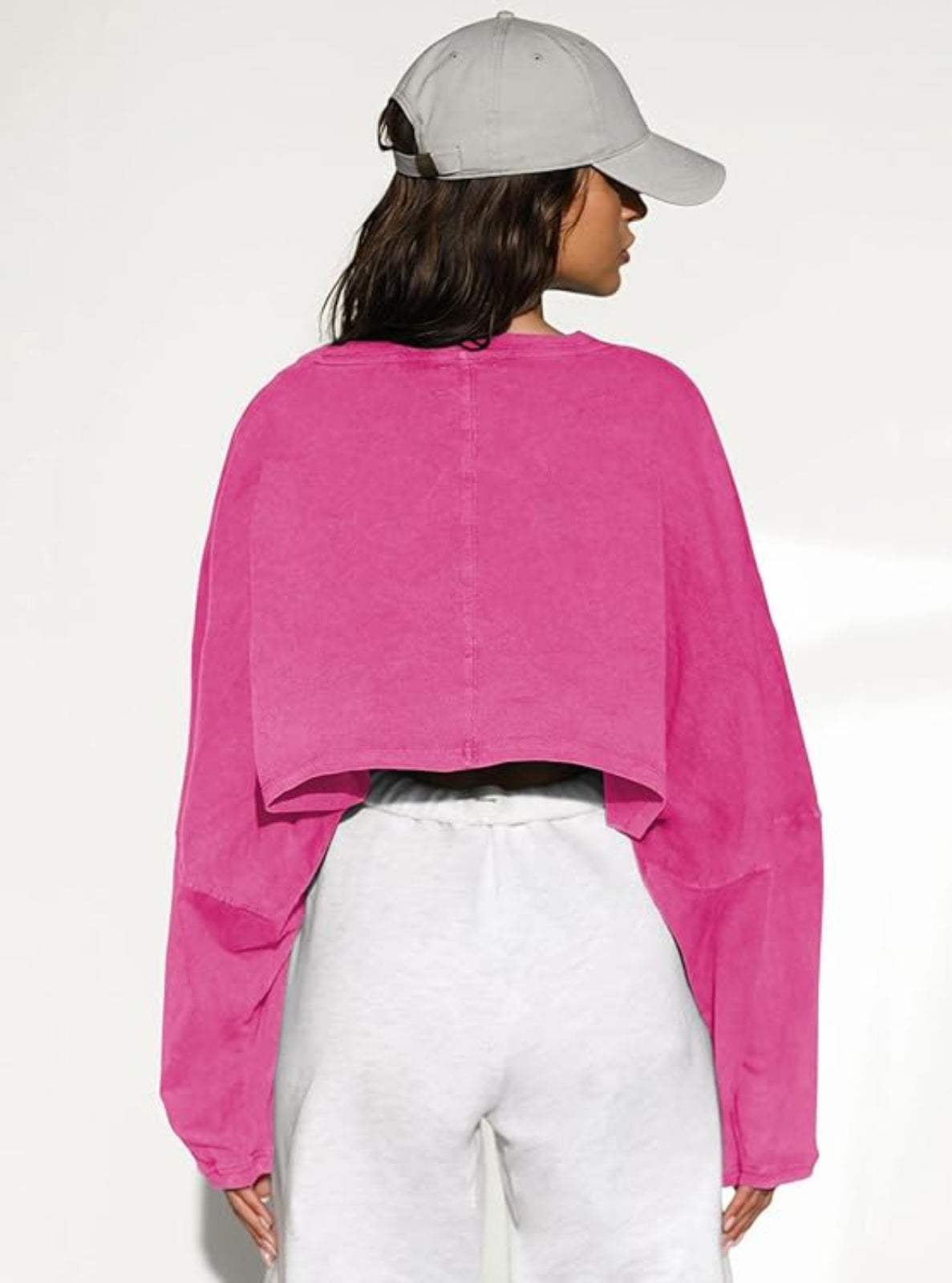 Person wearing a bright pink shirt and white pants against a white background