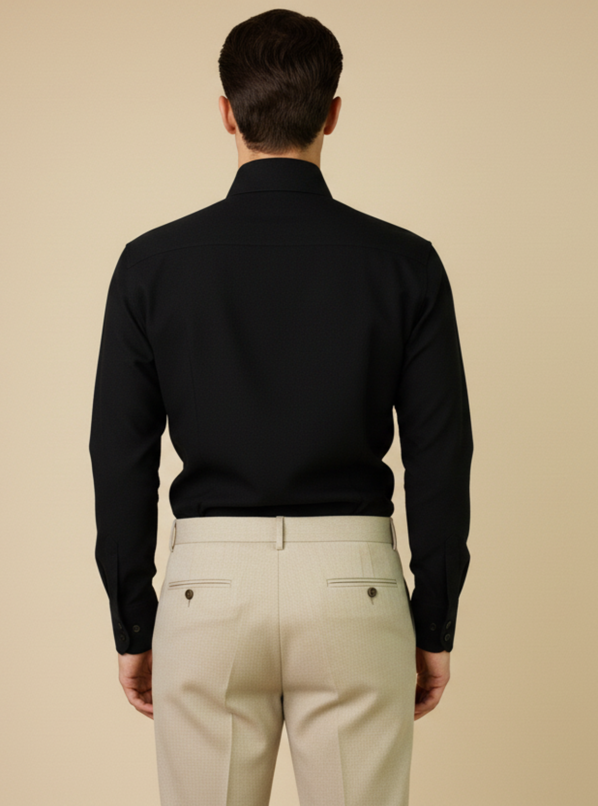 Man wearing a black shirt and beige pants against a beige background