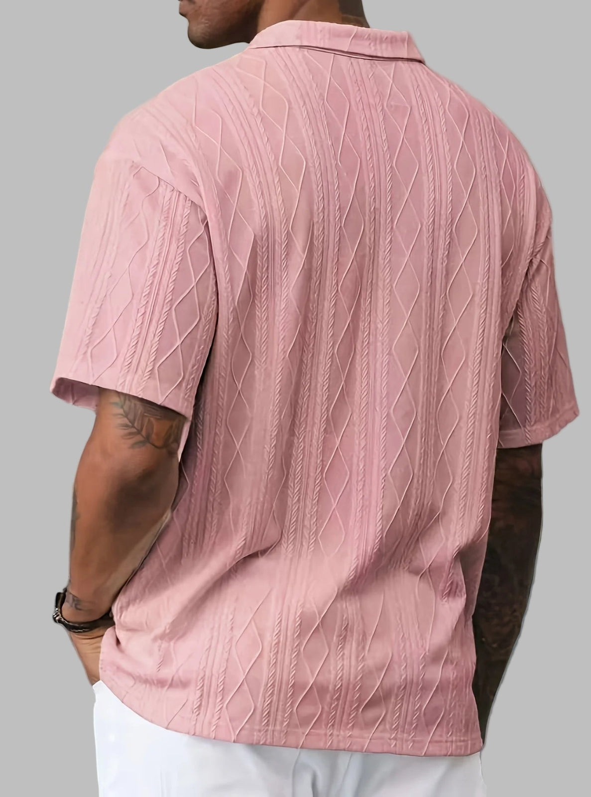 Person wearing a pink textured polo shirt with a neutral background