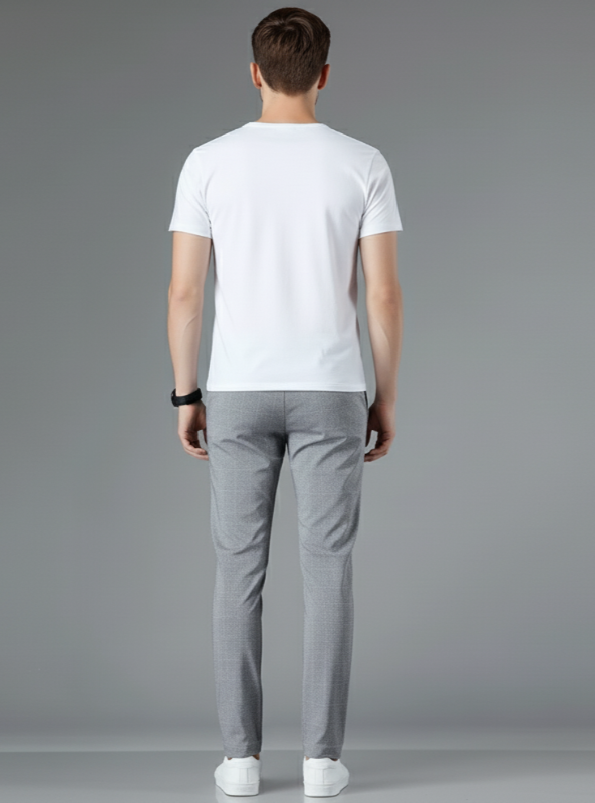 Man wearing a white t-shirt and gray pants on a gray background